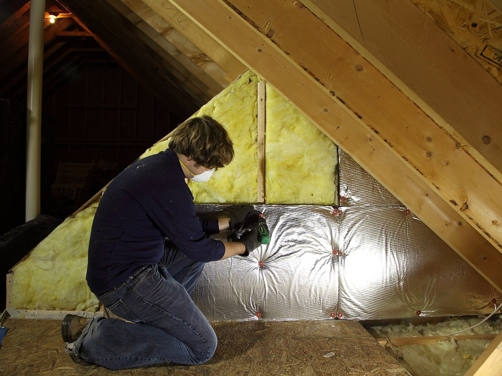 Technician installing insulation in a residential attic