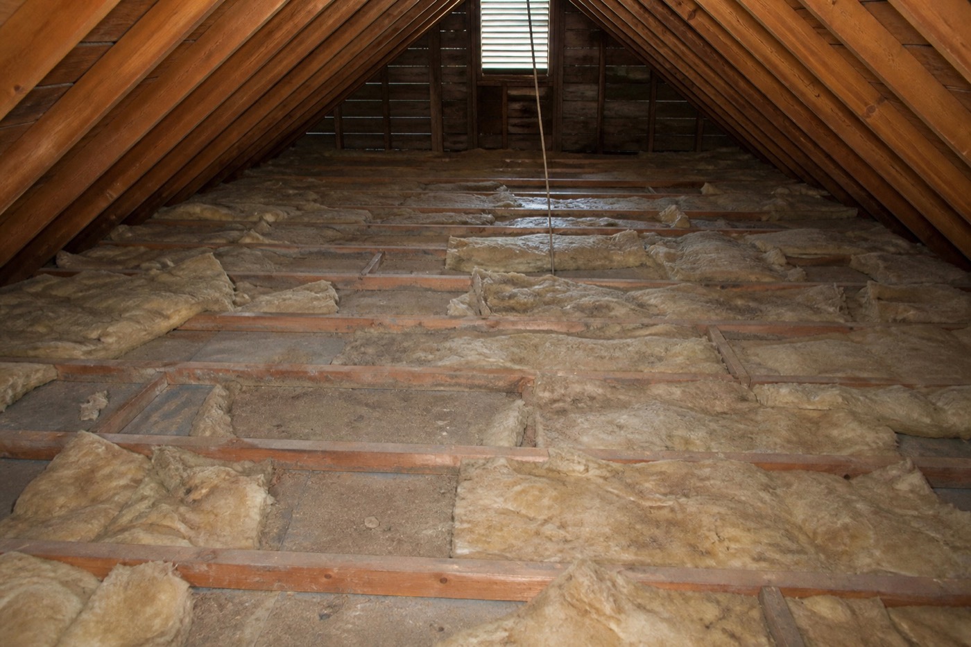 Thin patchy attic insulation with exposed joists and top plates