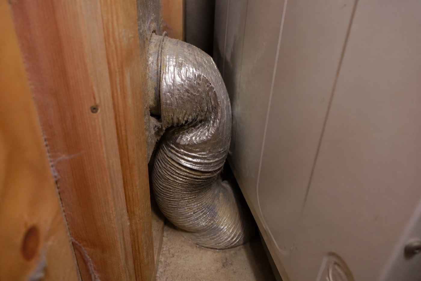 Crushed flexible dryer vent hose pinched behind a residential dryer